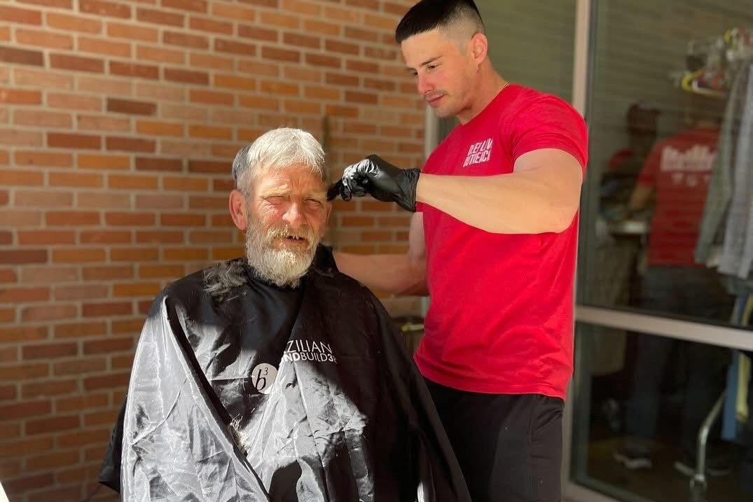 Nash cutting a man's hair at a community outreach event