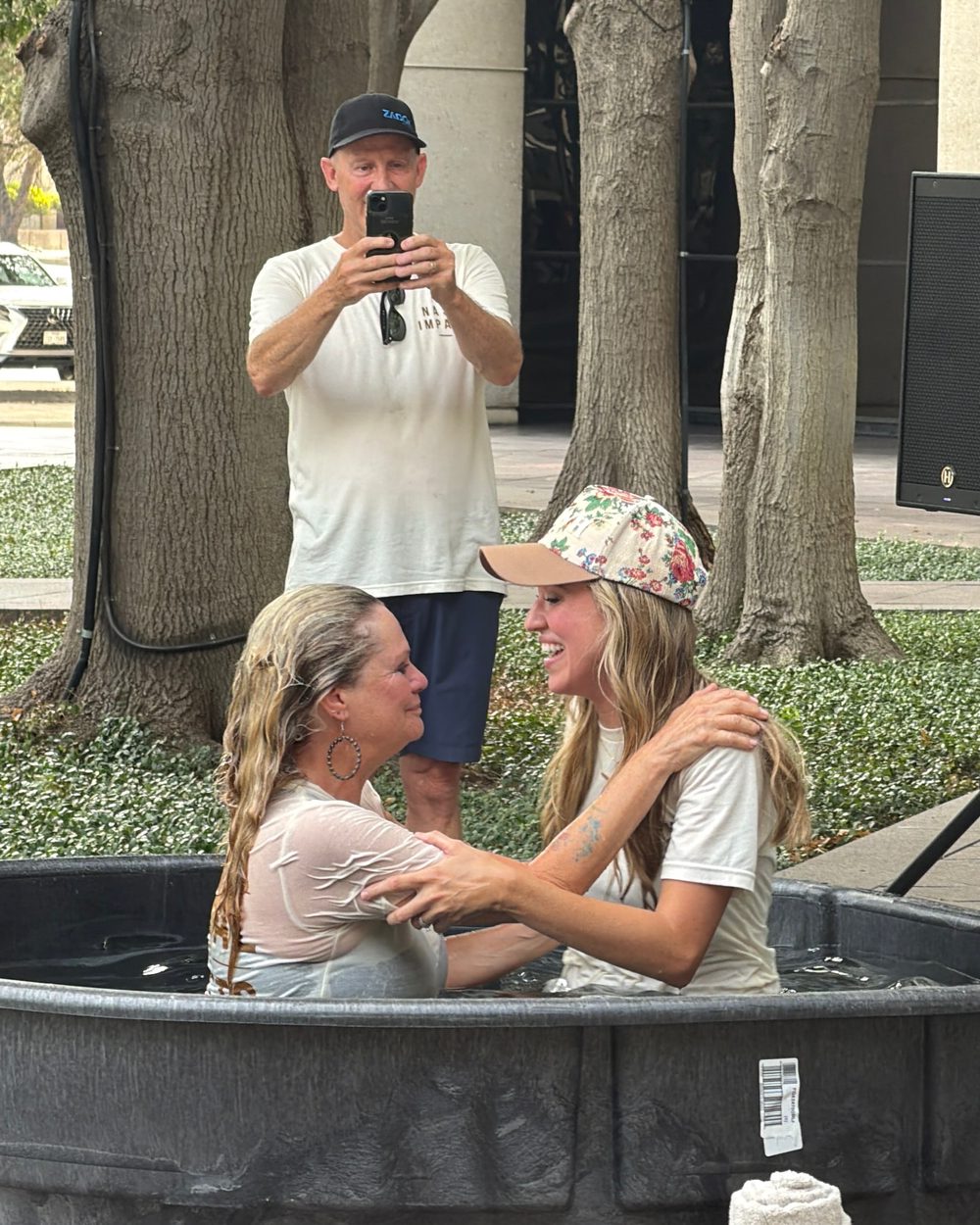 Kelsey baptizing Karla, Nash&rsquo;s mother, as they embrace in the baptism tub