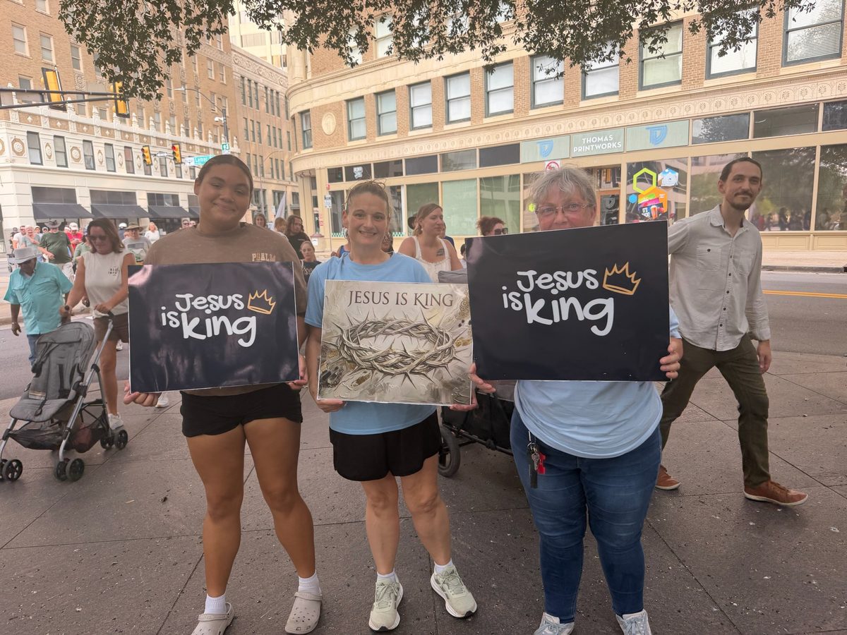 Three women holding signs that read Jesus is King during the march
